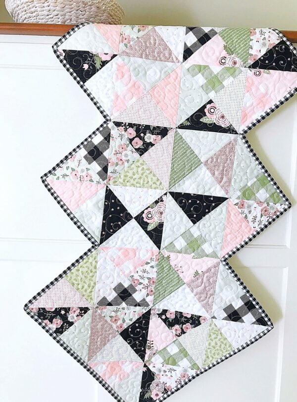 Rhapsody Whirl table runner pattern for 1 charm pack and features a zigzag edge.